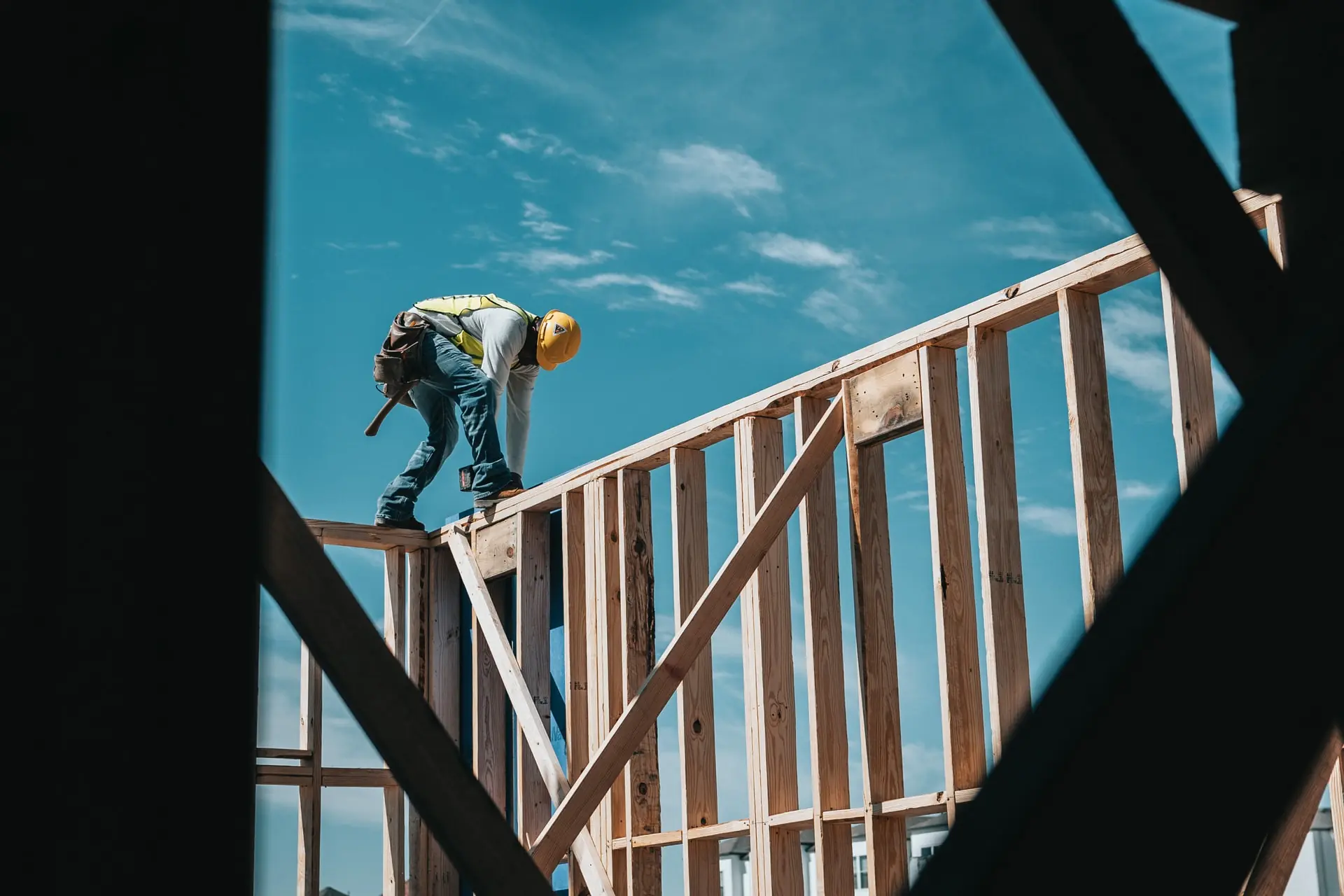 Zimmerer auf einer Holzkonstruktion vor blauem Himmel